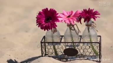 鲜花在玻璃瓶金属篮站在沙滩上的沙子，然后专注的字快乐制成
